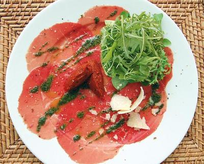 Rucola-Salat auf Rinder-Carpaccio mit Pesto, Chili-Olivenöl und gehobeltem Parmesan - 
